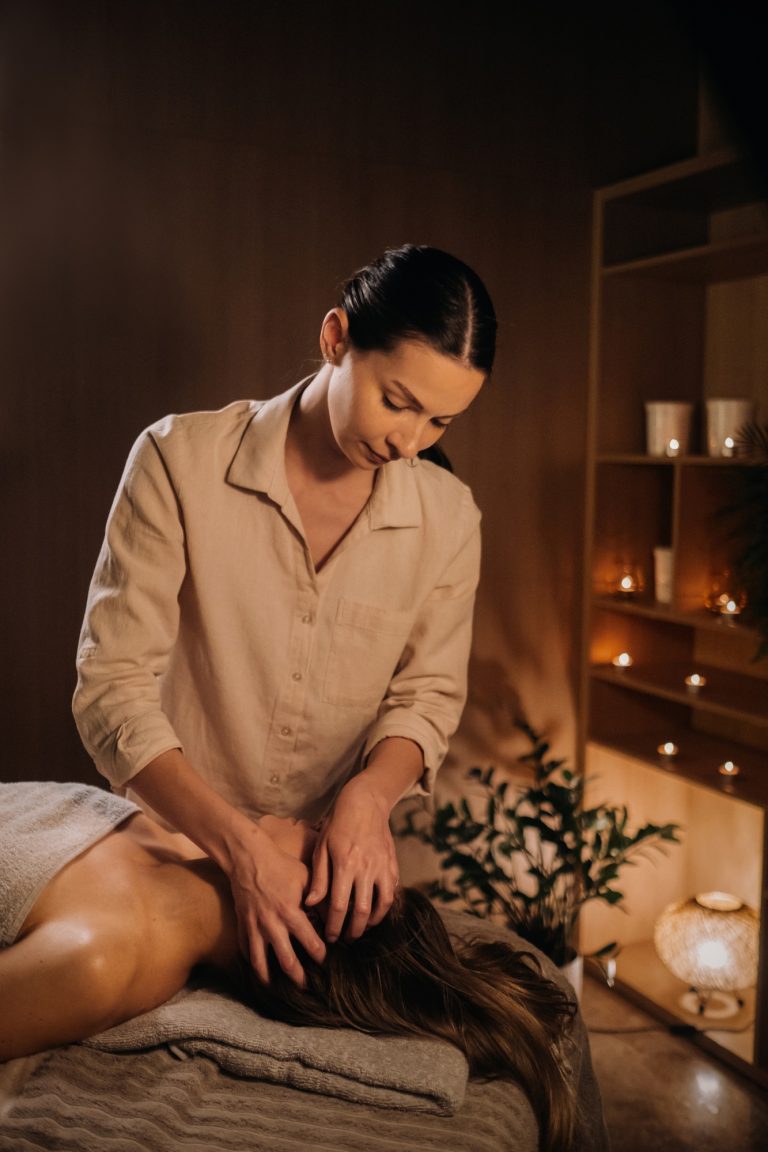 A masseuse gives a head massage to a woman at the spa. A professional masseur massages the head of a