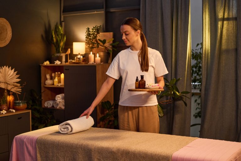 Smiling Masseuse Preparing Massage Table